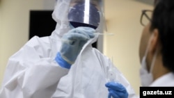 Медработник в защитной одежде производит забор анализов на коронавирус у пациента.