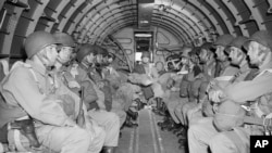 Parașutiști americani în interiorul unui avion militar în timp ce survolează Canalul Mânecii în drum spre coasta franceză a Normandiei pentru invazia aliată din Ziua Z.