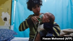 A Syrian boy holds an oxygen mask over the face of an infant after an alleged chlorine gas attack in eastern Ghouta.