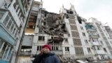 A local resident reacts next to the building where her destroyed apartment is located in the besieged city of Mariupol