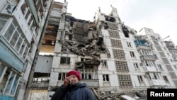 Локална жителка до зградата во која се наоѓа нејзиниот уништен стан во опколениот град Мариупол. 28.03.2022.