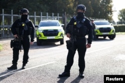 Armed police officers stand guard on a road outside the perimeter of the RAF Fairford airbase on September 28.