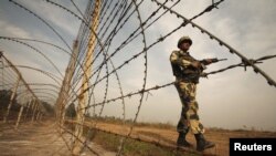 An Indian Border Security Force soldier patrols near the fenced border with Pakistan in Suchetgarh, southwest of Jammu.