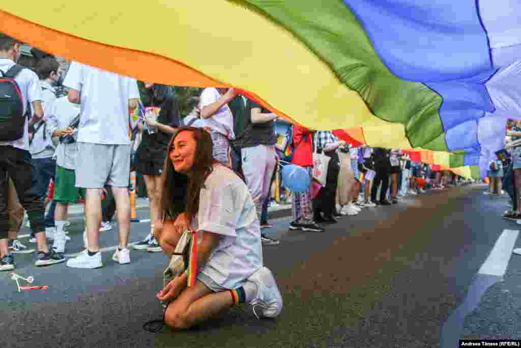 O femeie pozează sub steagul curcubeu, simbolul LGBT, pe Calea Victoriei din București.