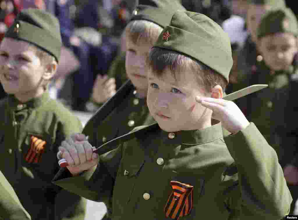 Boys dressed in historical military uniforms salute the parade commander. They are wearing the St. George Ribbon, a symbol of the World War II victory that is also widely used by supporters of separatism in eastern Ukraine.