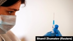 A health-care worker prepares a dose of Sputnik V vaccine against COVID-19. Hundreds of people in Moscow demonstrated on June 26 in opposition to what they said were "mandatory" vaccinations.