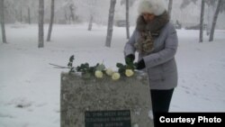 Павлодардағы саяси қуғын-сүргін құрбандарына арналған ескерткіш-тасқа Жаңаөзен құрбандарына арнап гүл шоқтарын қойып жатқан қала тұрғыны. Сурет Facebook әлеуметтік желісінен алынды. 16 желтоқсан 2012 жыл.