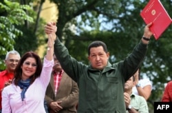 Венецуелският президент Уго Чавес (дясно) държи протокол от нова конституционна поправка, която му позволява неограничено преизбиране. Чавес държи за ръка Силия Флорес, която по това време е председател на Националната асамблея. Каракас, 19 февруари 2009 г.