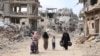 Palestinian women and children walk on a dirt road lined with building rubble in Gaza City on October 7, the first anniversary of Israel's war in the Gaza Strip.