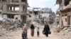 Palestinian women and children walk on a dirt road lined with building rubble in Gaza City on October 7, 2024, on the first anniversary of ISrael's war in the Gaza Strip.