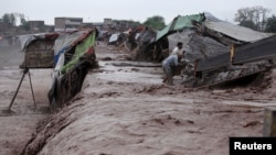 Men collect try to collect their belongings from a makeshift shop on the outskirts of Peshawar after it was hit by flooding following torrential rain in Khyber Pakhtunkhwa Province on April 3. 