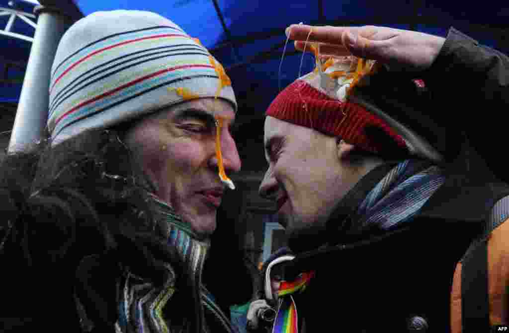 Gay-rights activists brave rotten eggs thrown at them by antigay Orthodox believers during a &quot;kiss-in&quot; protest outside the State Duma in Moscow. Russian legislators had planned to debate a bill that would introduce sanctions for providing minors with information on homosexuality. (AFP/Andrey Smirnov)