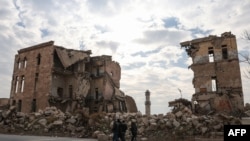 Syria - Syrians walk past one of Aleppo's destroyed structures near the northern city's historic citadel on December 5, 2024,