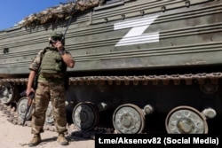 Російський військовослужбовець на тлі військової техніки із Z-символікою