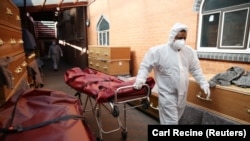 Un angajat în echipament special la o moschee din Birmingham, Marea Britanie, transformată temporar în morgă