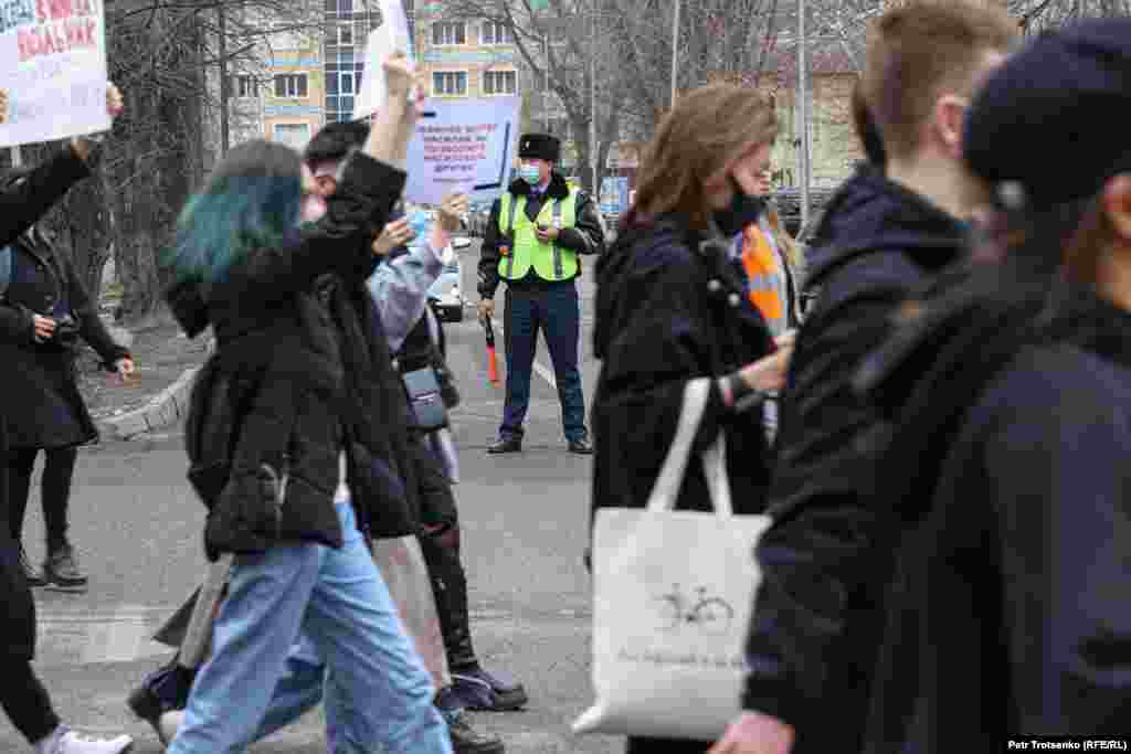 Сотрудник полиции наблюдает за порядком во время женского марша в Алматы.