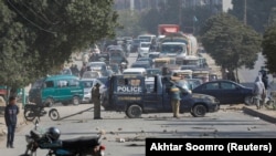 A police vehicle is parked on a road covered with stones thrown by protesters in Karachi on January 7, the fifth day that demonstrations against the killing of 11 Shi'ite Hazara coal miners brought cancellations and delays to roads, railways, and airlines.