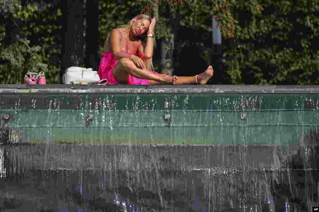 A Russian woman sits at a fountain on a hot day in St. Petersburg.