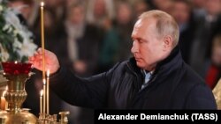 Vladimir Putin aprinde o lumânare în timpul unei liturghii de Crăciun, în 2019. Biserica Ortodoxă Rusă sărbătorește Crăciunul în conformitate cu calendarul iulian.