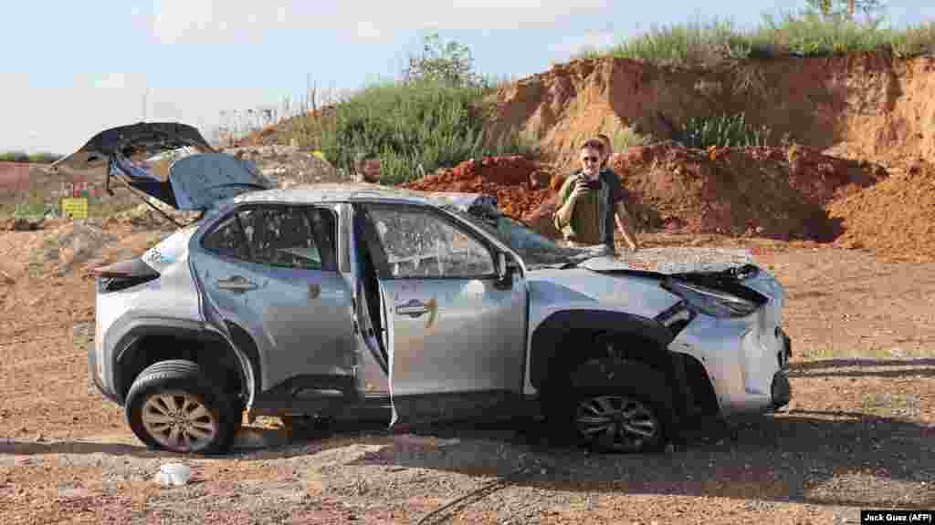 Muškarci gledaju oštećeni automobil u Tel Avivu. Razmjeri štete od iranskih napada ostaju nejasni. Poznato je da je jedan Palestinac poginuo od pada rakete u gradu Jerihonu na Zapadnoj obali.