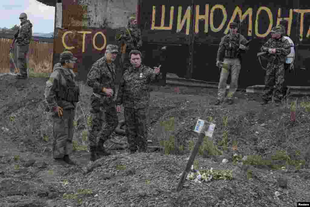 Бойовики угруповання «ДНР» стоять біля могили з написом «Загинули за путінську брехню. Напис на могилі п’ятьох загиблих товаришів, як стверджували у ЗМІ та соцмережах відразу після виявлення могили, зробили російські військові. Нижня Кринка Донецької області, 23 вересня 2014 року