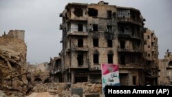 Syria - Syrians walk by a poster in Arabic that reads, "Thank you guardians of the homeland," in Aleppo, January 18, 2018. 
