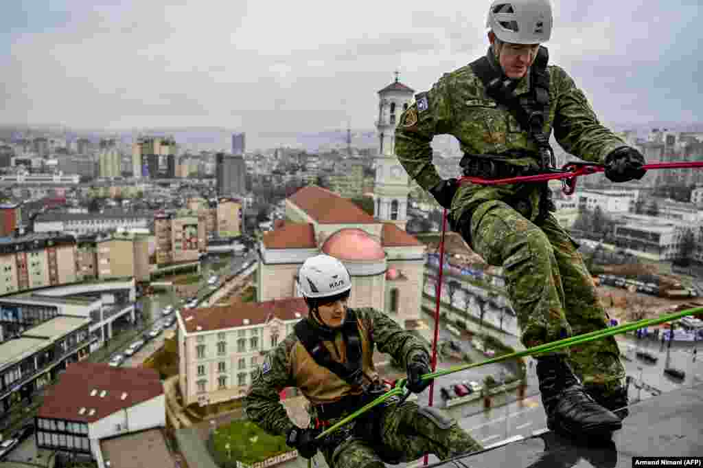 Kosovar soldiers abseil in Pristina as they hang a giant banner to thank Kosovo&#39;s health workers on the front lines of the COVID-19 pandemic. (AFP/Armend Nimani)