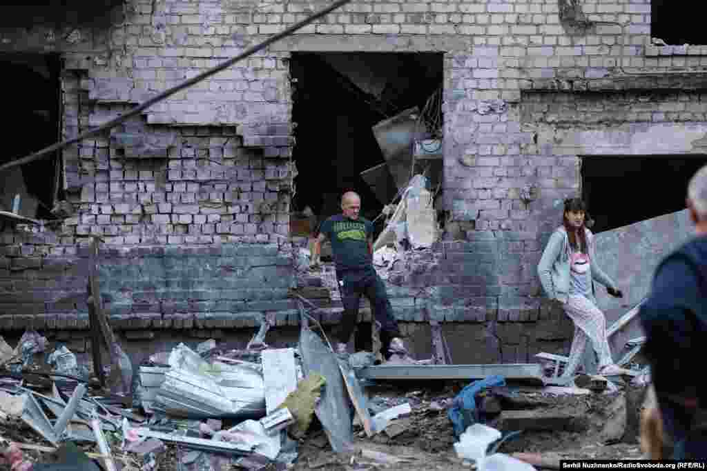 Жителі понівеченого російським ударом будинку в Борисполі намагаються знайти якісь свої речі, що були викинуті вибуховою хвилею з квартир.  Київська область, 1 вересня 2026 року
