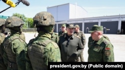 Аляксандар Лукашэнка ў 465-й ракетнай брыгадзе падчас вучэньняў па «баявым ужываньні ядзернай зброі і ядзерным забесьпячэньні». На фоне — новапабудаваныя ангары для комплексаў «Іскандэр-М»