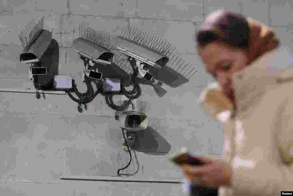 Женщина использует свой телефон, проходя мимо камер наблюдения в Санкт-Петербурге, Россия, 2 февраля 2026 года. REUTERS/Антон Ваганов