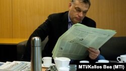 Viktor Orbán citind presa maghiară… ajutat de multe cafele.