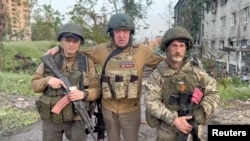 Šef Wagnera Jevgenij Prigožin(u sredini) pozira sa dvojicom svojih plaćenika dok daje izjavu o povlačenju svojih snaga iz zaraćenog ukrajinskog grada Bakhmuta 25. maja 2023.