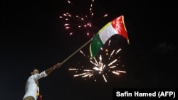 Iraqi Kurds wave the Kurdish flag as they celebrate in the streets of the northern city of Irbil on September 25.