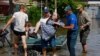 A member of Russia's Emergencies Ministry and a local resident carry an elderly woman during the evacuation of residents from a flooded area in the town of Hola Prystan in the Kherson region of Russian-controlled Ukraine on June 8.