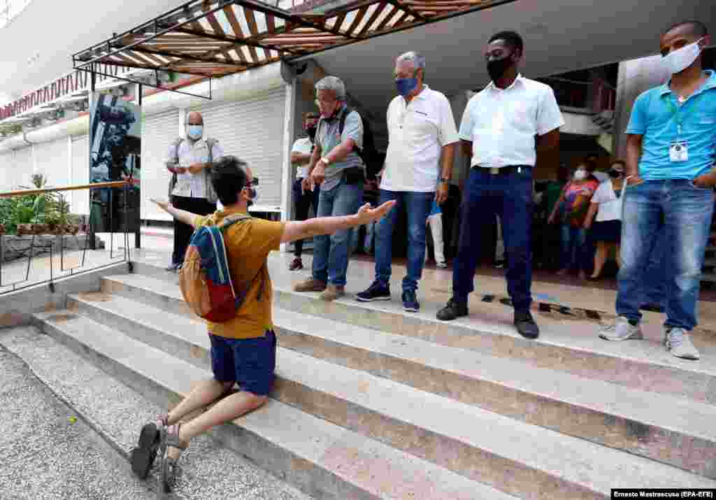 Un protestatar din Havana îngenunchează în fața angajaților Radiodifuziunii publice.