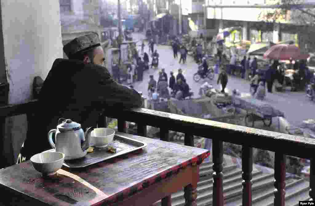 A man watches the market crowd from the second floor of a teahouse. - The densely packed houses and narrow lanes of old Kashgar are said to be the best-preserved examples of a traditional Islamic city in all of China. (All photos www.ryanpyle.com)