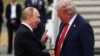 Руският президент Владимир Путин (вляво) и американският му колега Доналд Тръмп в първото им ръкостискане в Аляска. На заден план се виждат стълбите на самолета Еър Форс 1, с който пътува американският държавен глава.