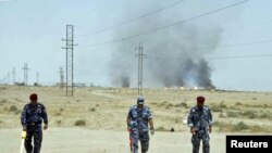 Iraqi police scan for land mines near the Rumaila oil field in Basrah province.