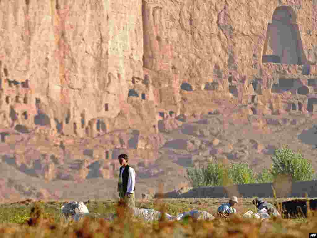 Afghanistan -- A Hazara youth works on a farm in front of the cave-monasteries and the niches where the 174-foot Buddhas, Bamiyan, 25Sep2009 - This photograph taken on September 25, 2009, a Hazara youth works on a farm in front of the cave-monasteries and the niches where the 174-foot Buddhas, which were destroyed by the Taliban, once stood in Bamiyan.