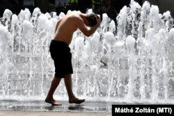 Hőségriasztás alatt fürdik egy kisfiú a Szabadság téri szökőkútban Budapesten, 2021. június 19-én