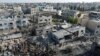 Palesztinok állják körül a romokat egy izraeli légicsapás után a Gázai övezet déli részén fekvő Hán Júniszban 2023. október 14-én