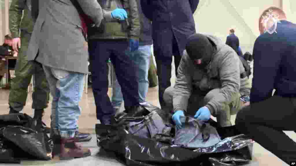 In this photo taken from video released by the Investigative Committee of Russia on March 23, investigators work at the scene after the mass shooting at the Crocus City Hall concert venue the evening before.