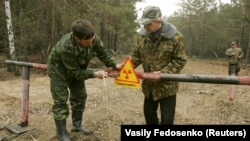 A 2006 file photo of workers fixing a radiation warning sign near the village of Babchin, Belarus 