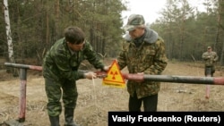 Архівне фото 2006 року, на якому зображено робітників, які встановлюють знак попередження про радіаційну небезпеку поблизу села Бабчин, Білорусь. Фото: Василь Федосенко (Reuters)