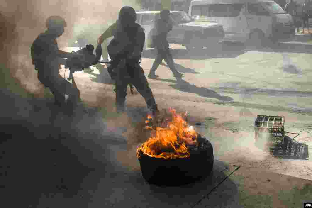 Egyptian riot policemen douse burning tires thrown by supporters of the Muslim Brotherhood during their rally to mark the first anniversary of the military ouster of Mohamed Morsi. (AFP/Khaled Desouki)