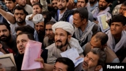 Afghans gather outside the passport office in Kabul on October 6 after Taliban officials announced they will start issuing passports to its citizens again.