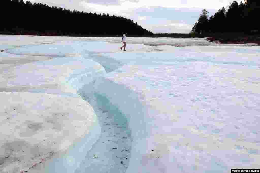 A woman walks on the surface of the glacier, which covers over 1,000 hectares. Thanks to dozens of meters of permafrost underneath, the ice doesn&rsquo;t melt, even during exceptionally hot summers.