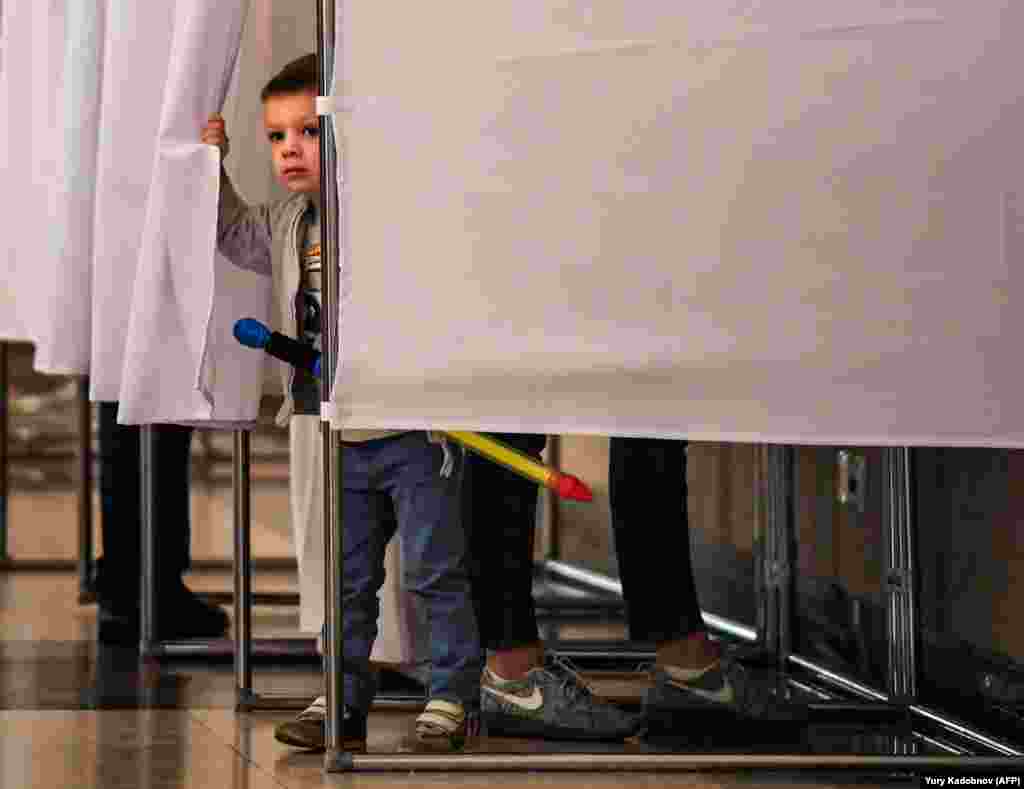 A boy peeps out from behind the curtains of a voting booth at a polling station during the municipal elections in Moscow on September 10. (AFP/Yury Kadobnov)