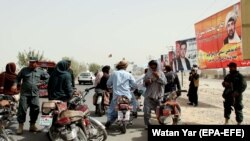 Afghan security officials check people on a roadside in Helmand as security has been intensified ahead of the upcoming parliamentary elections.