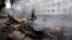 A masked man jumps over a burning barricade in front of police headquarters in the embattled southeastern port city of Mariupol on May 9.